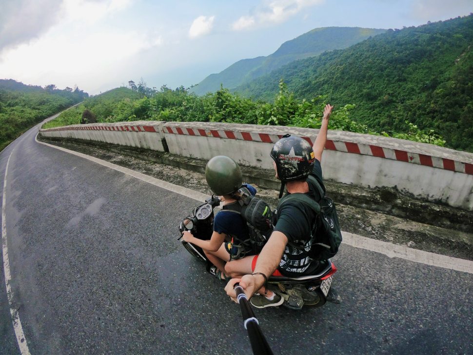 Two men riding on a motorbike on a mountain road